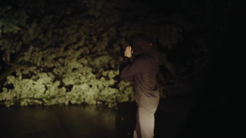 Man standing outside on the phone at night with a flashlight