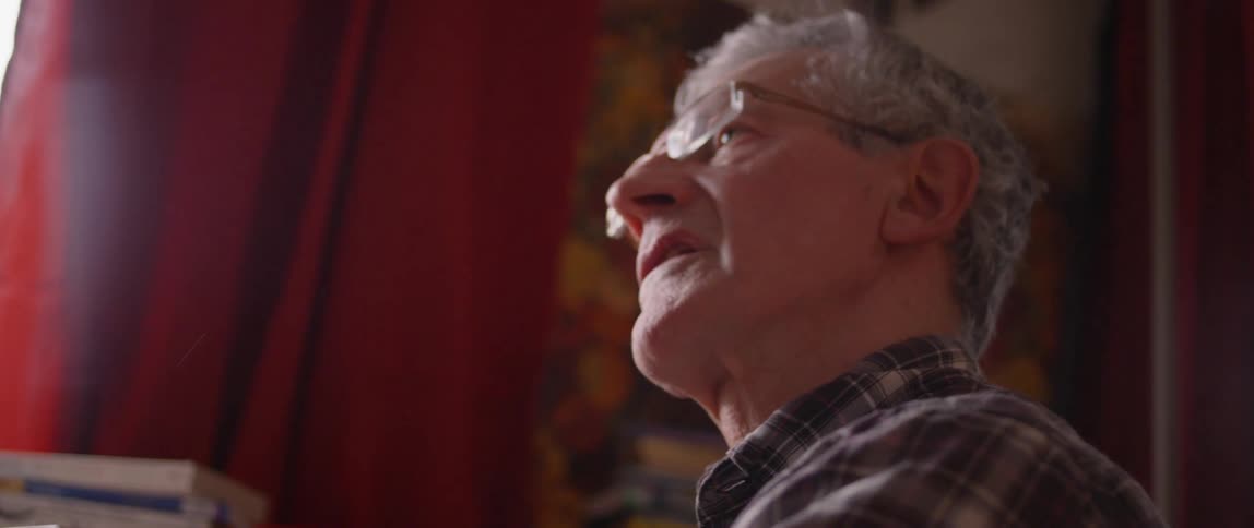 Elderly man sits talking in a house
