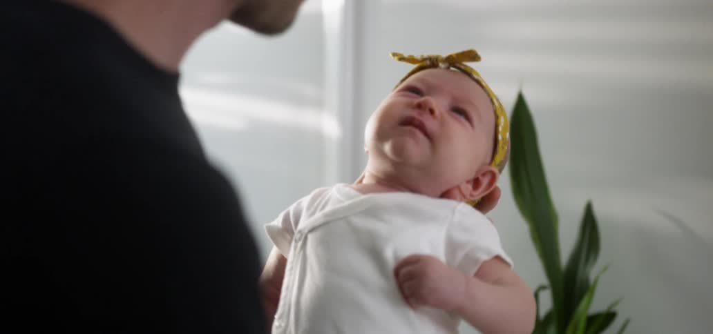 Man holds an infant that cries and waves its hand