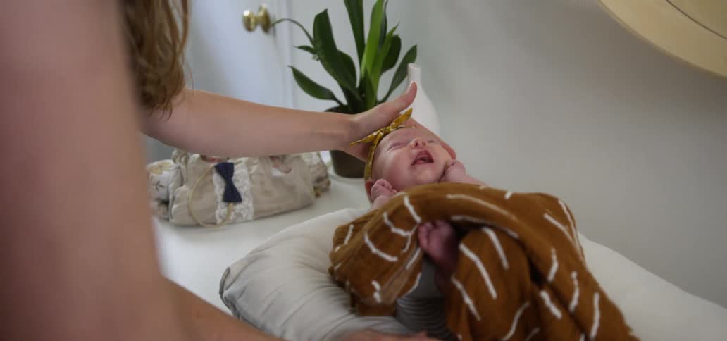 A woman soothes a baby on a changing table