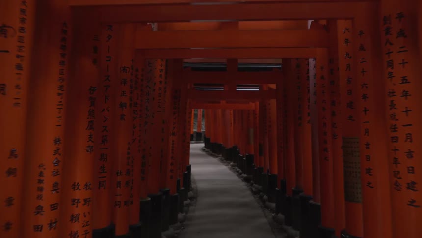 Ancient tunnel made of orange gates with carved Japanese symbols