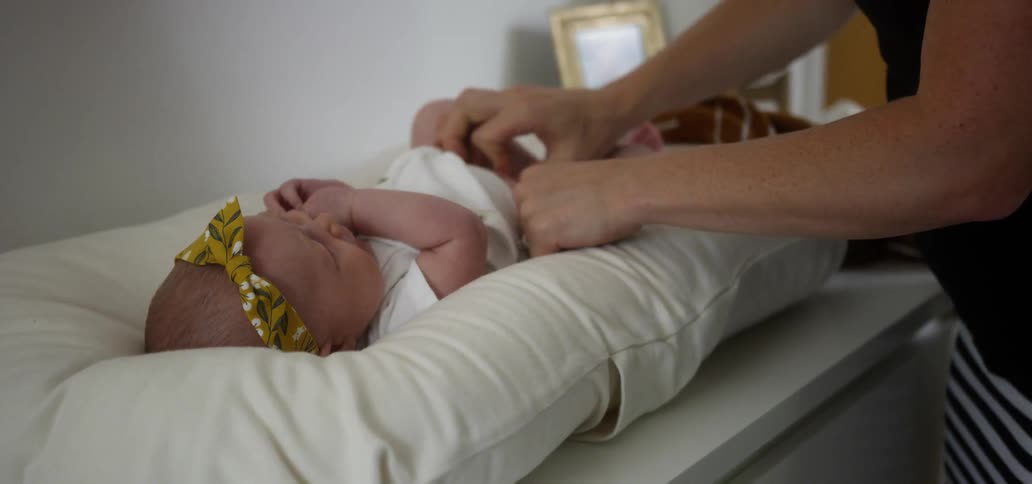 Person fastens a diaper on a small infant