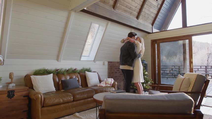 Man walks into to a living room to hug a woman