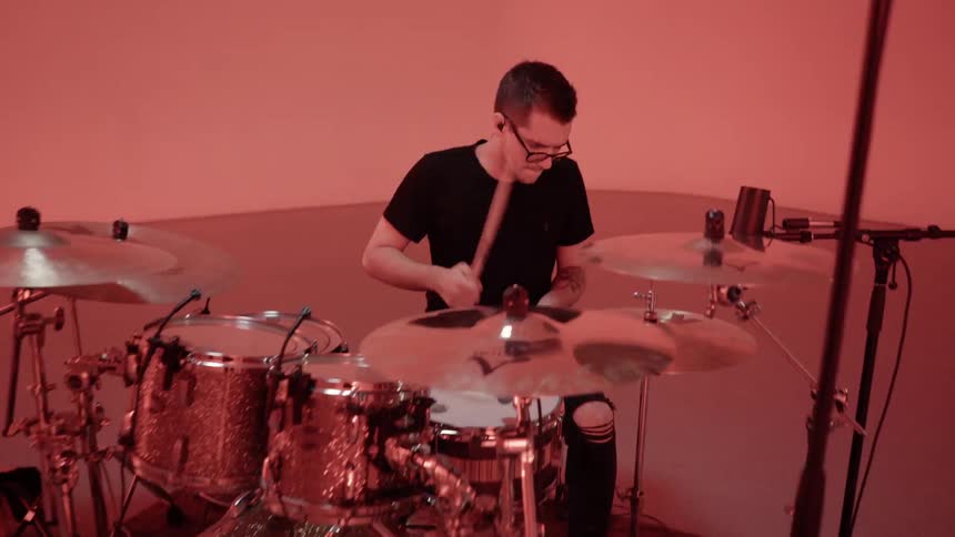A drummer plays in a room with flashing lights