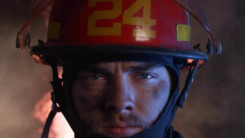 A firefighter stands in front of a fire