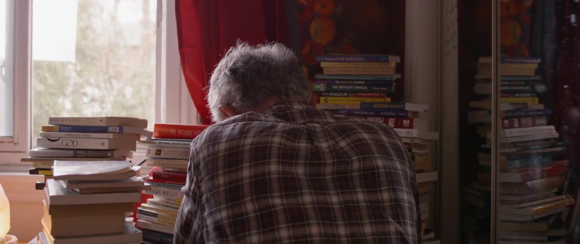 elderly man glances away before turning to his books
