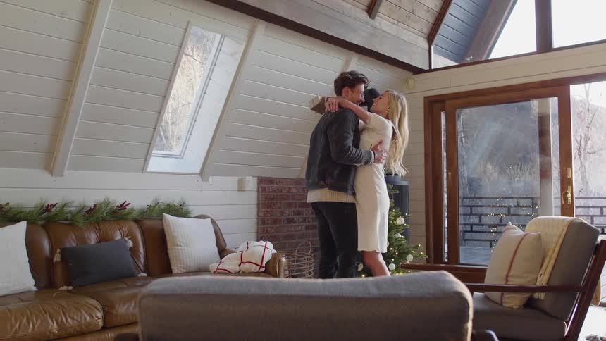 A man and woman hug and kiss in a living room