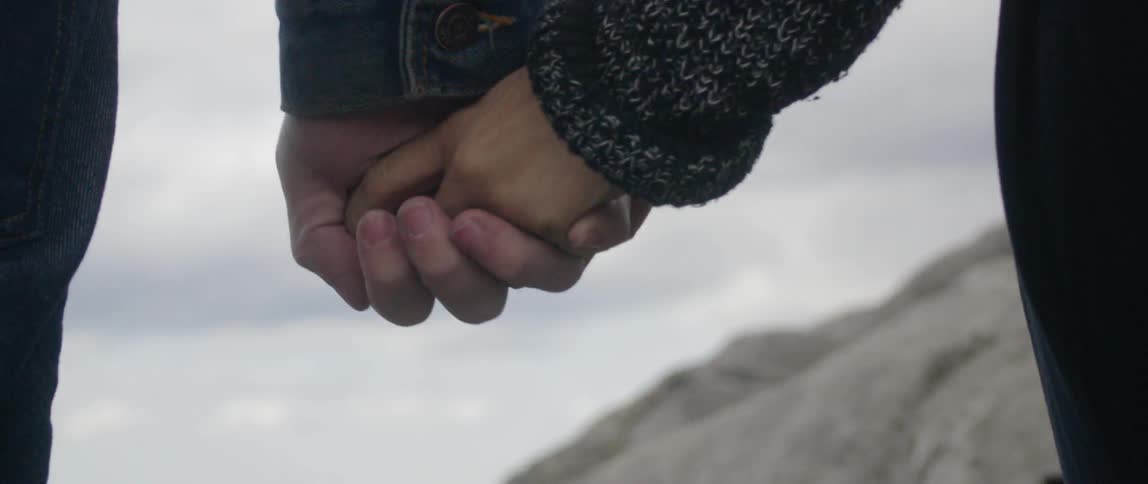 A man and woman hold hands outside