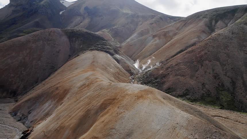 Steam pours from the stream between mountains