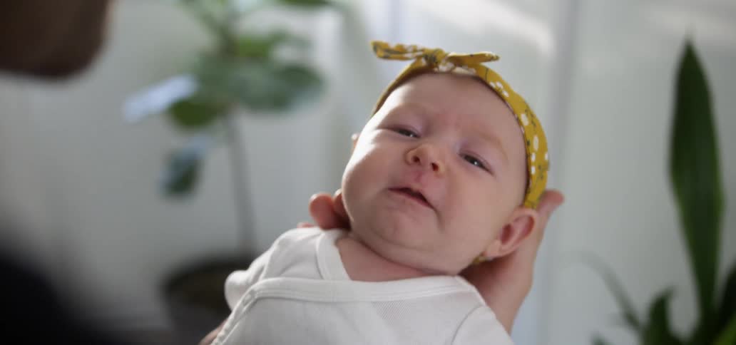 A dad holds his yawing infant in his hands