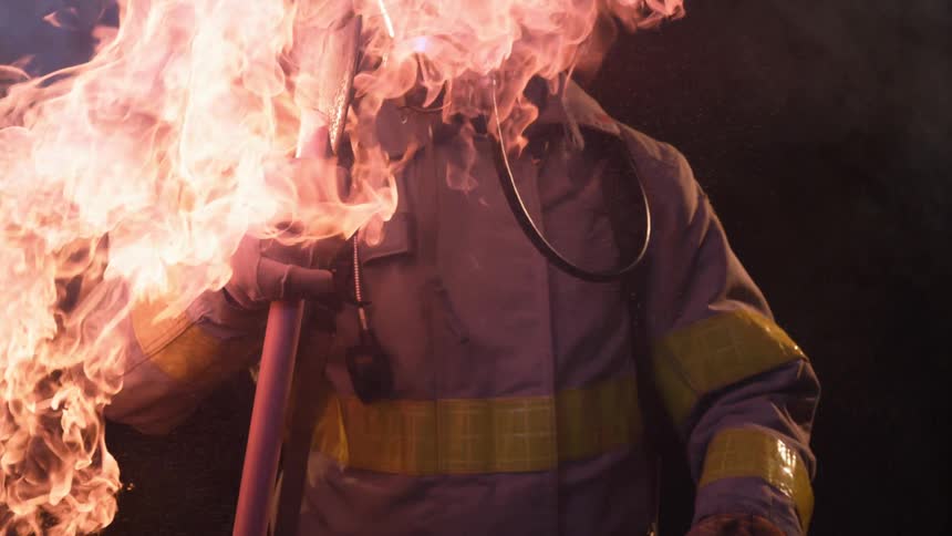Firefighter wearing mask stands near flames