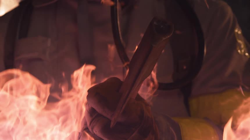 Firefighter holding axe stands in flames