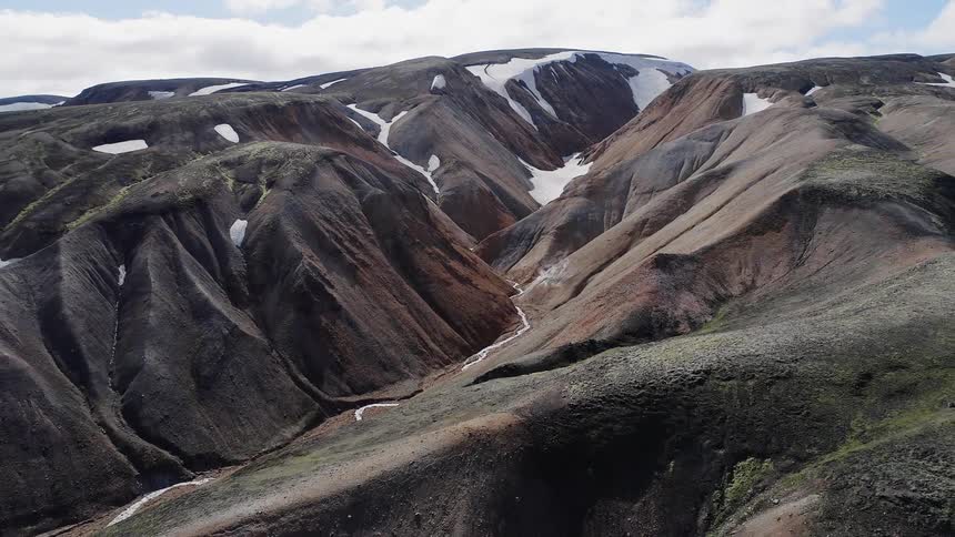 The mountain is high with some snow in the crevices