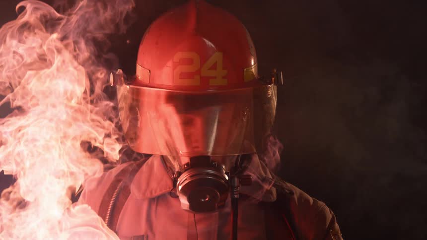 The fire covers the firefighter who leans through