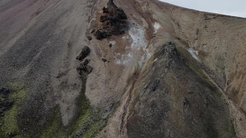 The mountain has green grass at the bottom
