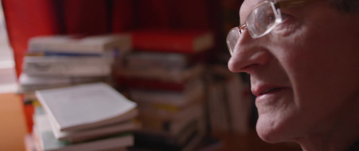 A man talks near a stack of books