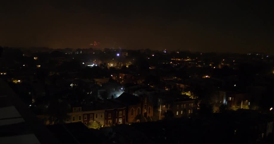 The town is dark with fireworks going off in the distance