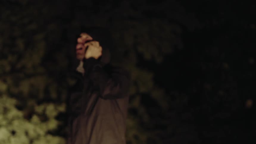 Man standing outside on the phone at night with a flashlight