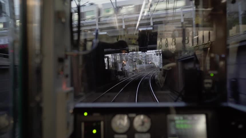 Train travels through a city with a bridge and a second train traveling overhead
