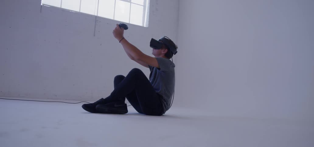 A man sits using a virtual reality headset