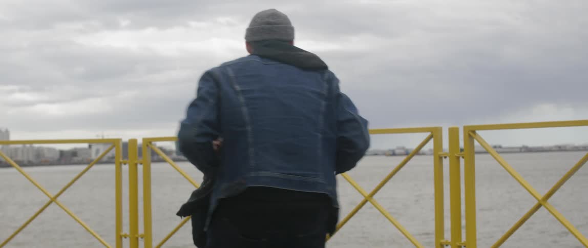 A man and woman spin around by the water together