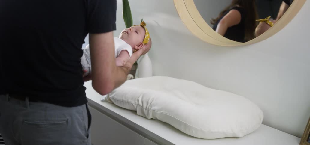Parents hold a baby in front of a mirror