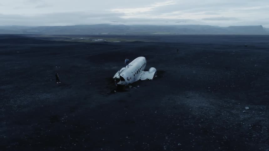 Broken airplane sits in a field as a man stands on top