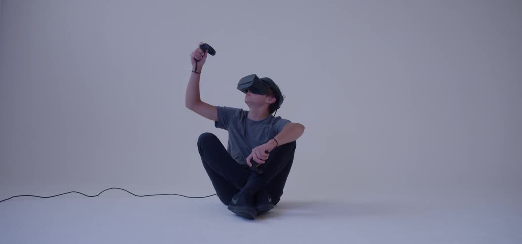 A boy uses a virtual reality headset in a white room