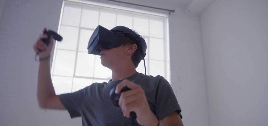 The man swings controllers using virtual reality