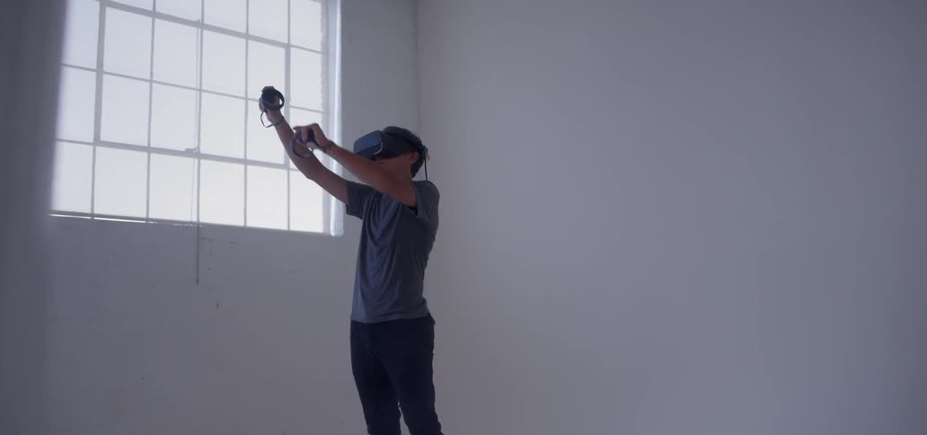A young man uses a vr headset in an empty room