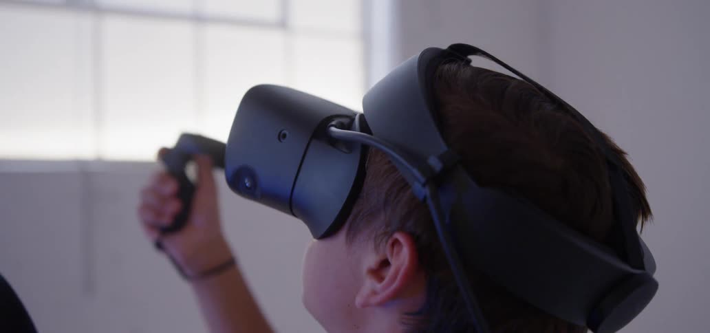 A boy is using a virtual reality headset inside in daylight
