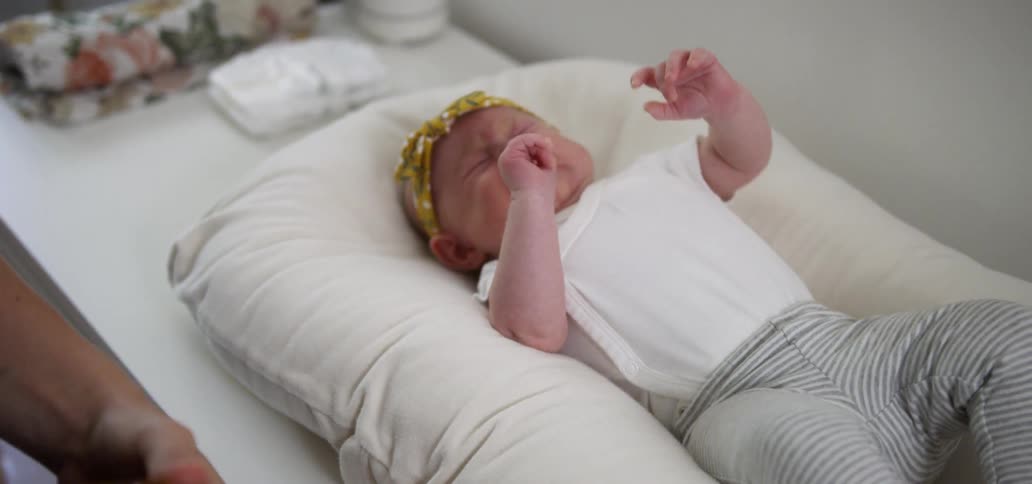 A woman places a baby down on a pillow