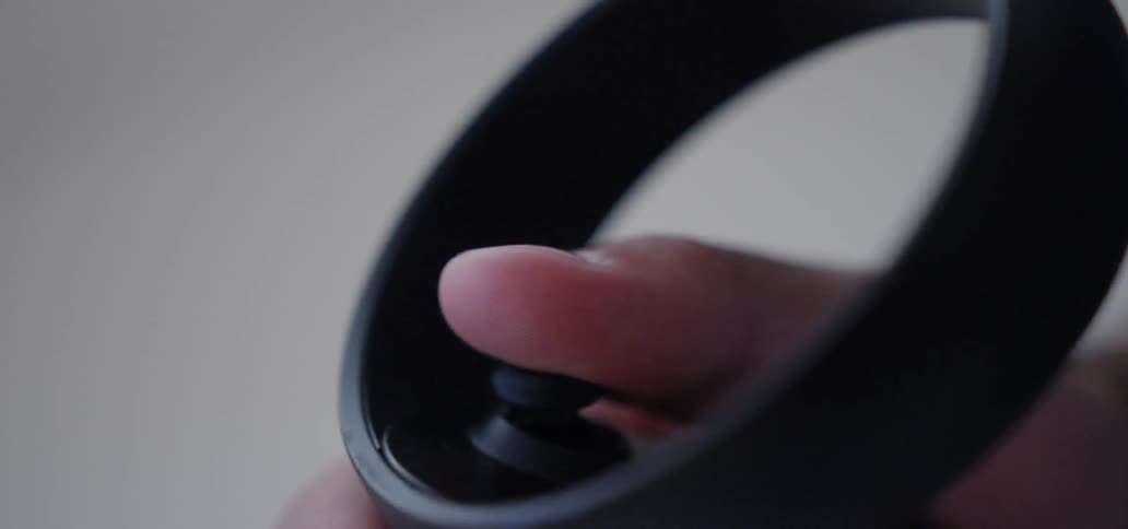 A thumb moves a joystick on a controller