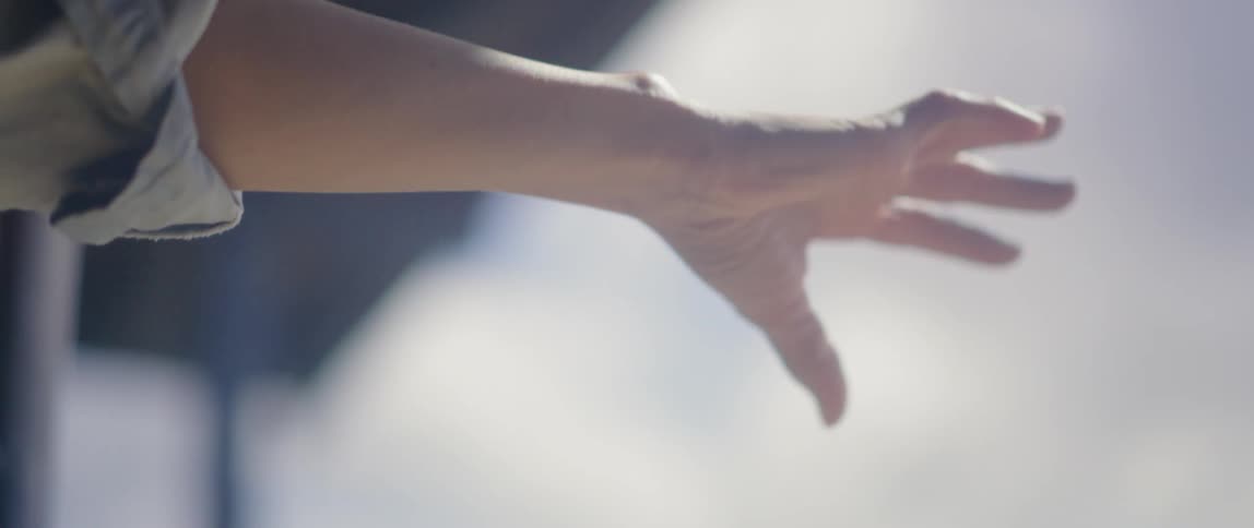 A woman reaches her hand through an open window