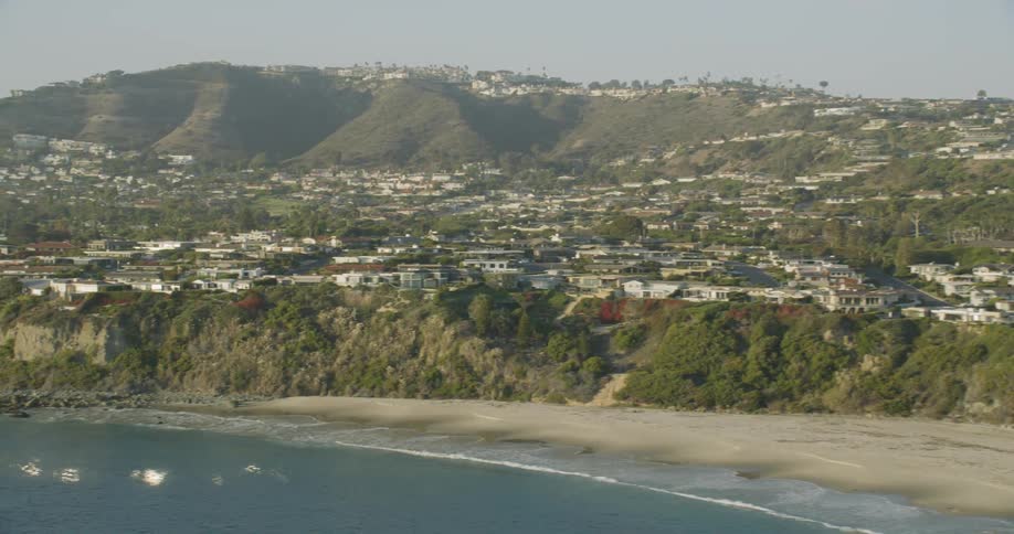 Ocean waves splash to shore next to a city on a cliff