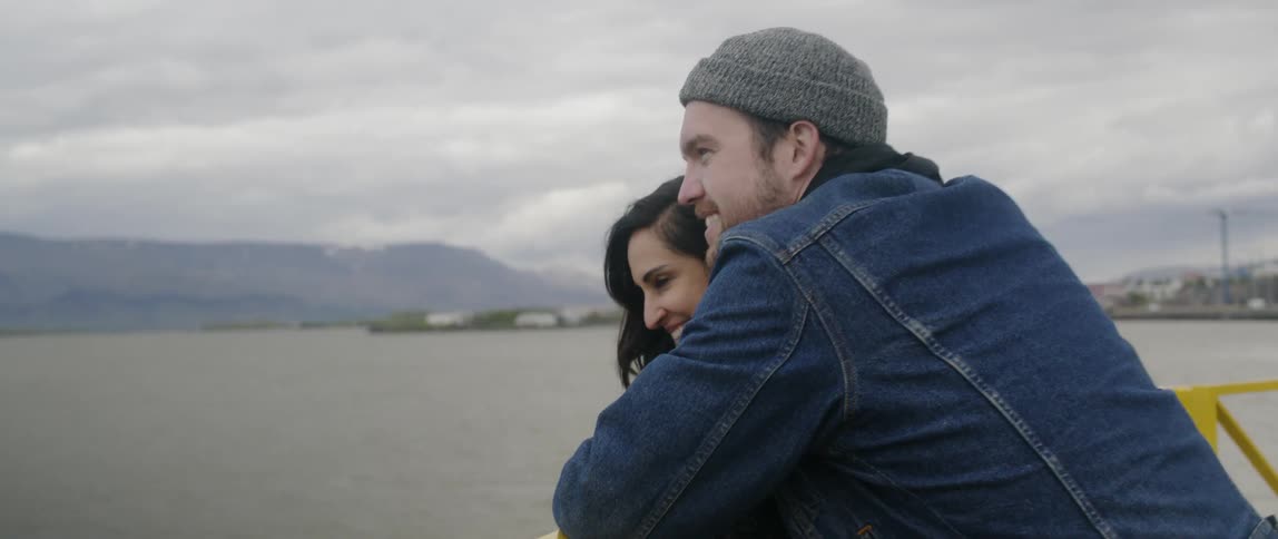 A man and woman sit together by the water