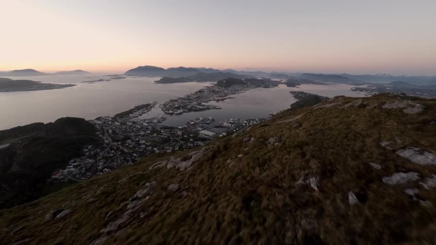View of mountainside, a town and a body of water located at the foot of a mountain