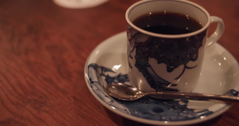 Cup of coffee sits on a saucer with a spoon