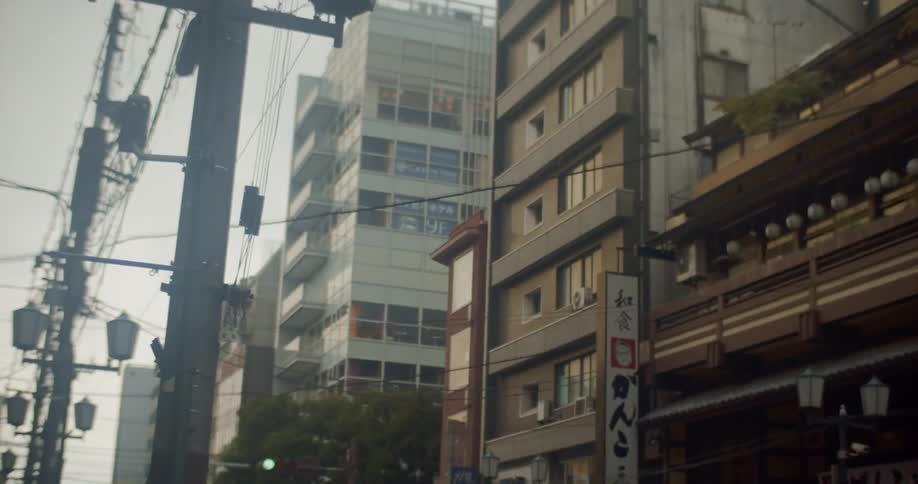 Power lines and light poles are lining the street of a district in an asian city in daylight