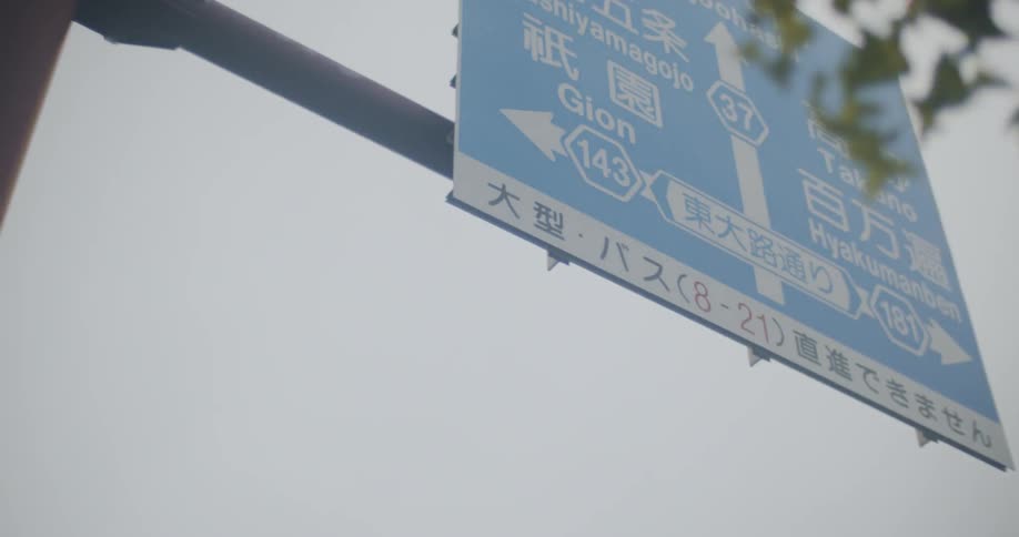The blue sign hangs in the cloudy sky