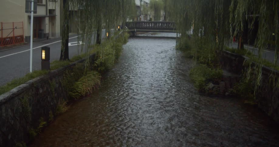 Shallow stream running between city streets on a cloudy day