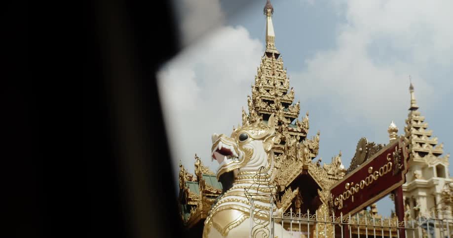 Statue outside of an ornate building with clouds overhead