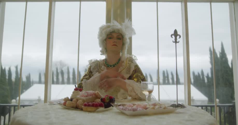 A woman in an old fashioned dress poses at a table