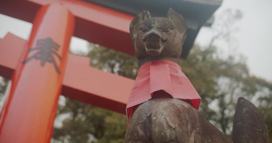 Statue of a dog with a red collar sits next to a red structure