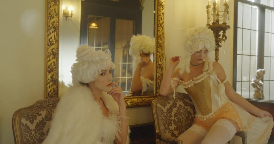 Women in old fashioned garb sit in chairs
