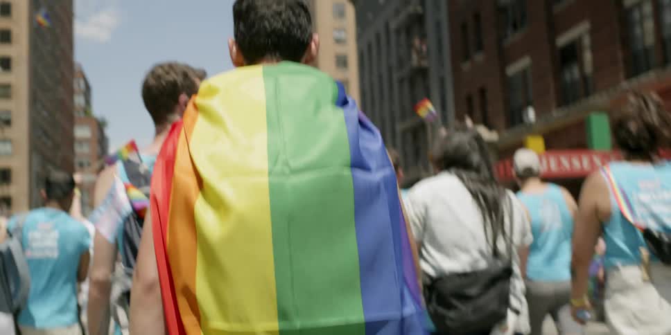 Man wrapped in rainbow flag marches in parade