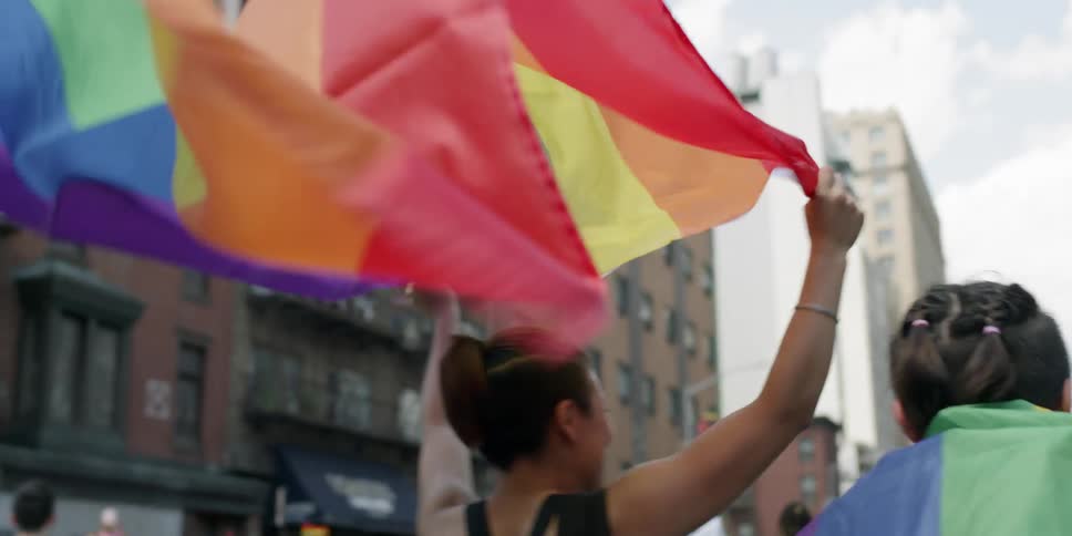 People are marching in a parade with rainbow flags