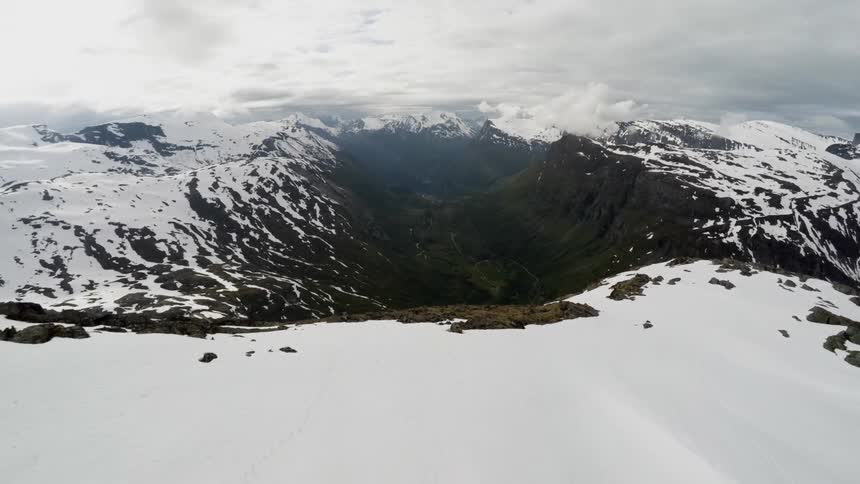A bird's-eye-view of snow covered mountains and two people walking on a mountain top