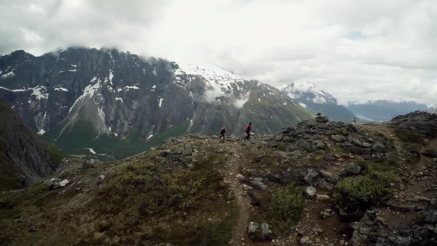 Two people hike mountains during the day