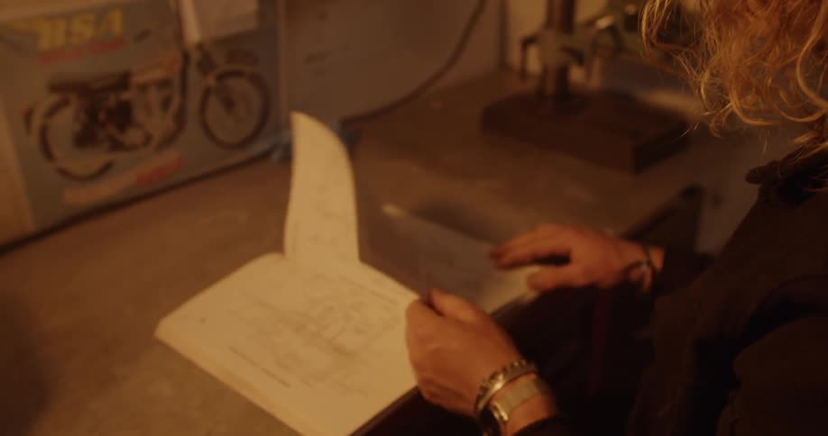 A person looks at an instruction manual at a workbench